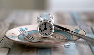 Clock on empty plate on table