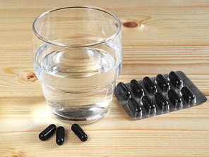 Charcoal binder capsules and glass of water